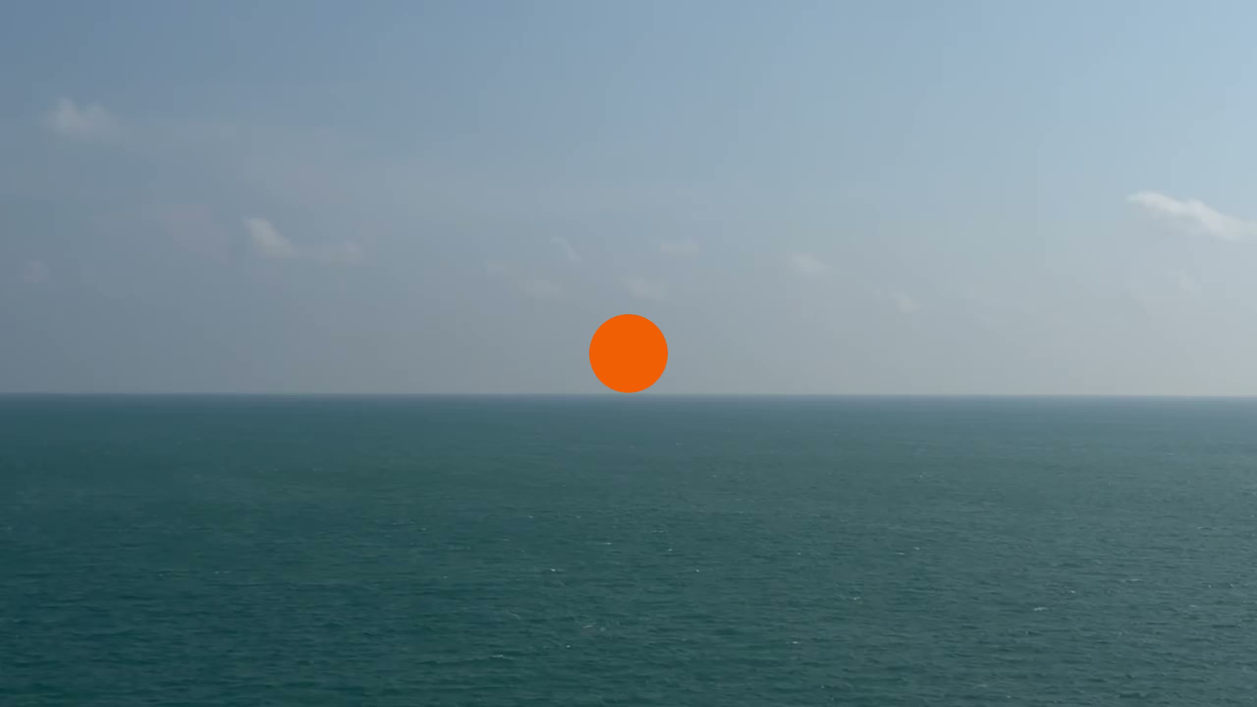 An orange circle over a film of the open sea